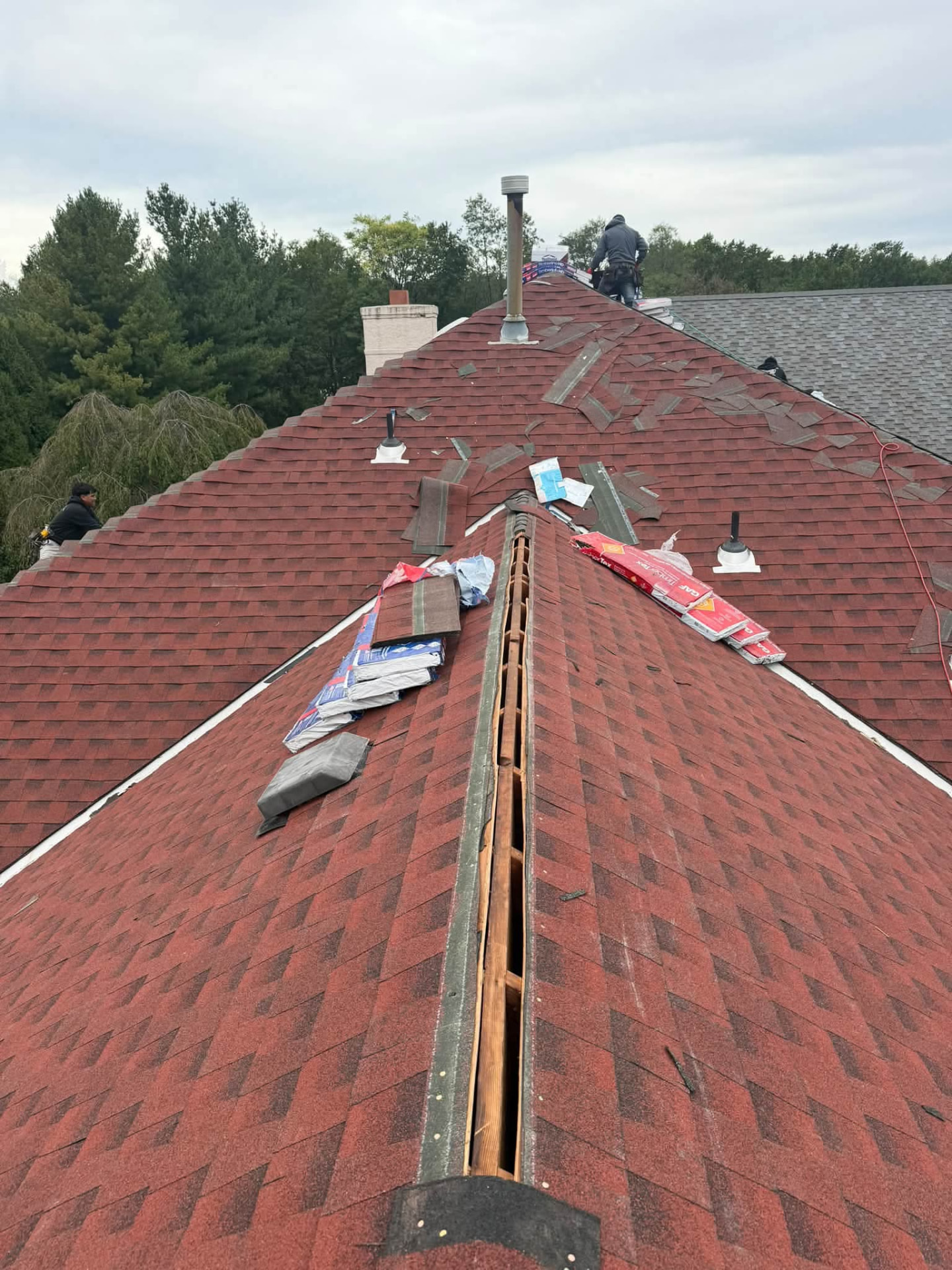 Ridge vent being installed on a red shingle roof